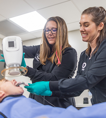 Two oral surgery team members taking x rays of a patients mouth