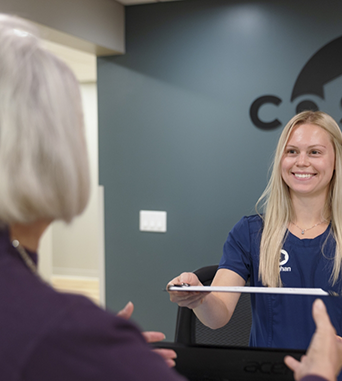 Front desk receptionist handing a clipboard to a patient