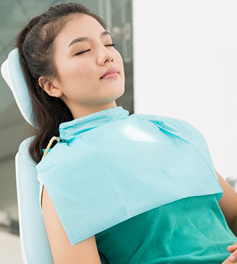 Woman leaning back in dental chair with her eyes closed