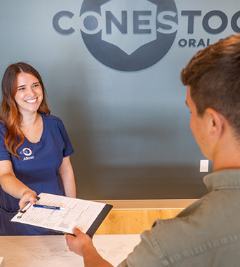 Receptionist handing a clipboard to a patient