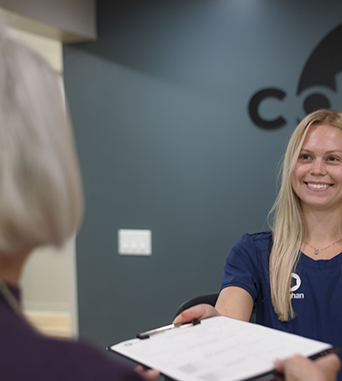 Oral surgery team member handing a clipboard to a patient