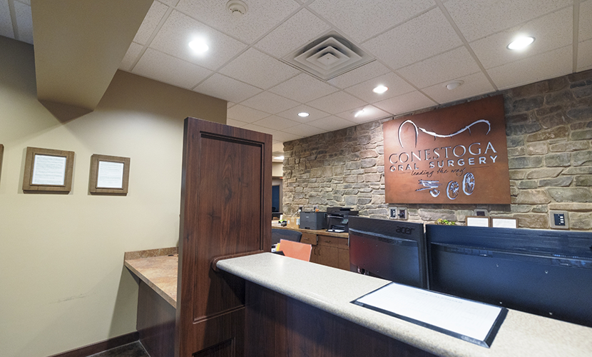 Front desk with Conestoga Oral Surgery sign on the wall behind it