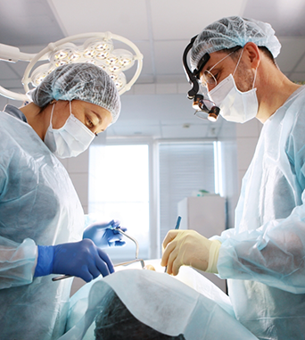 Oral surgeon and assistant performing jaw surgery on a patient