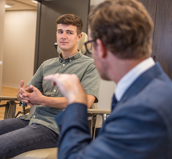 Young man in the treatment chair talking to his oral surgeon in Lancaster