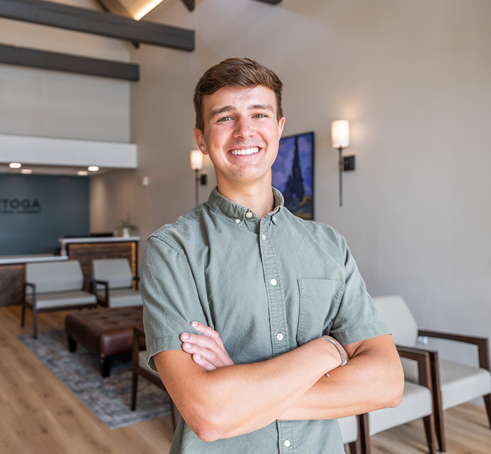 Young man smiling with his arms crossed in oral surgery office in Lancaster