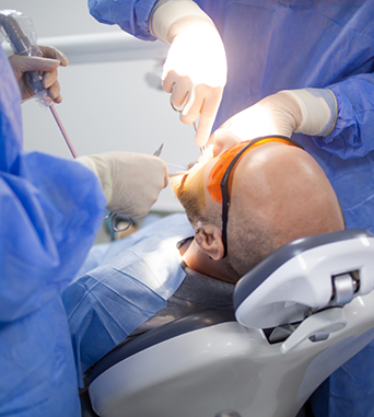 Oral surgeon and assistant performing surgical orthodontics on a patient