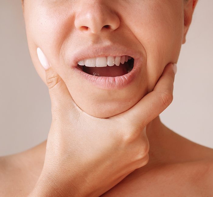 Person holding the sides of their jaw in pain before T M J treatment in Lancaster