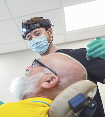 Oral surgeon smiling while talking to a patient in the treatment chair